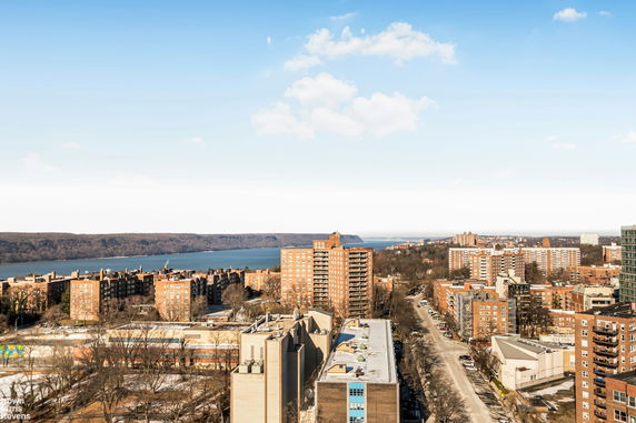 Panoramic view of a cityscape with tall buildings and a river in the background.