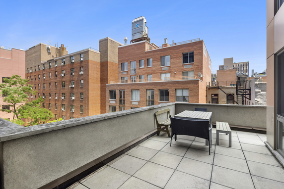 Rooftop area with seating and view of adjacent brick buildings.