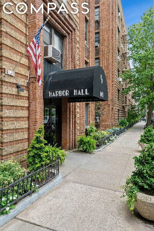 Front view of a multi-story brick building with an awning labeled Harbor Hall.