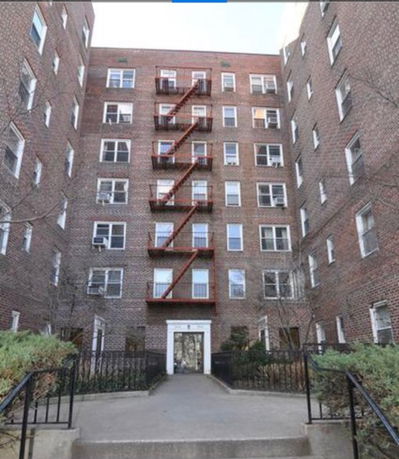 Front view of a multi-story brick apartment building with fire escape.