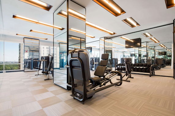 Interior view of a modern gym area with exercise equipment and mirrors.