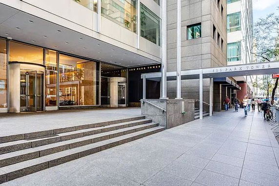 Entrance view of a multi-story office building with steps leading to revolving doors.