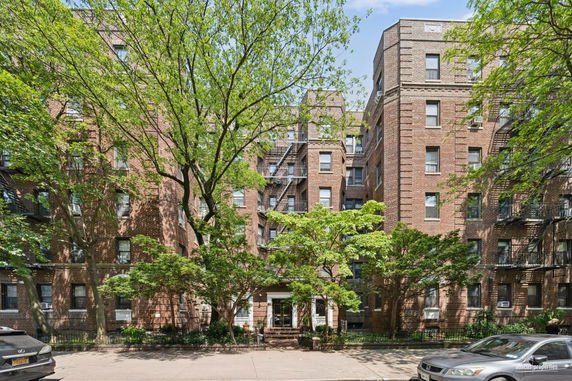 Front view of a multi-story brick apartment building with fire escapes.