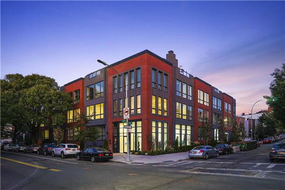 Front view of a modern three-story building with large windows on a street corner.