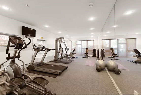 Indoor gym area with exercise equipment such as treadmills and weights.