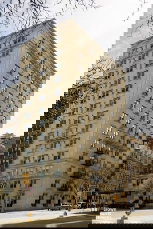 Front view of a multi-story residential building with numerous windows and a fire escape ladder on the side.