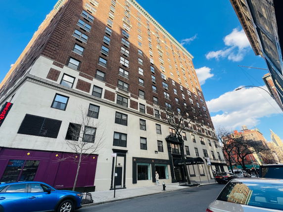 Front view of a multi-story brick and white building on a city street.