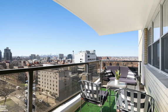 Balcony view overlooking a cityscape with distant skyscrapers and residential buildings.