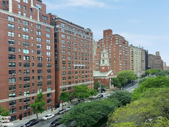 View of multiple multi-story brick buildings along a tree-lined street.