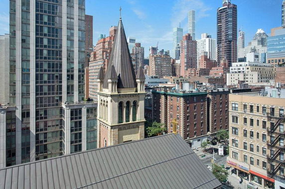 View of a city skyline with various buildings and a church tower.