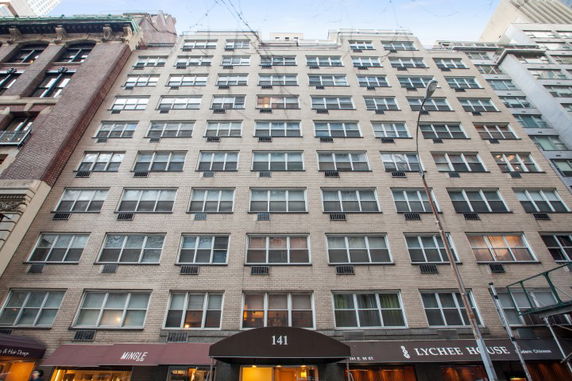 Front view of a multi-story building with uniform windows and ground-floor shops.