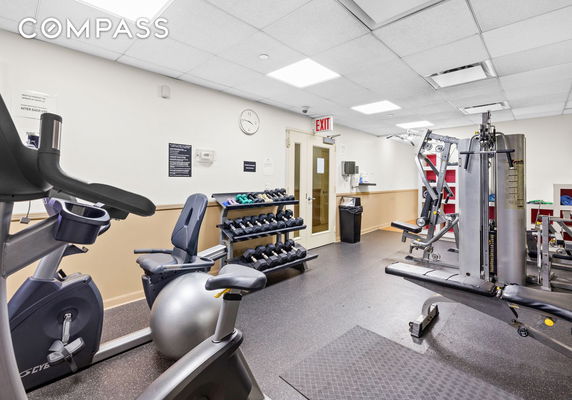 Indoor gym area with exercise equipment and weights.
