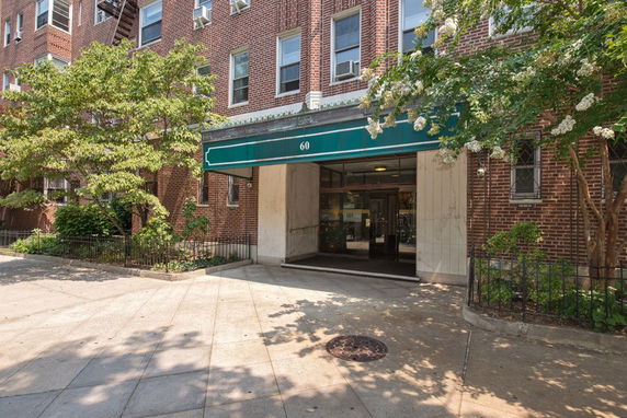 Front view of a brick apartment building with a green awning over the entrance.