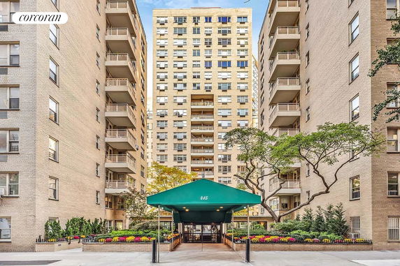 Front view of a multi-story residential building with a green awning entrance.