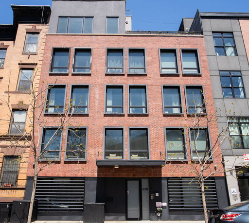 Front view of a multi-story brick building with large windows.
