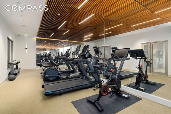 Interior view of a gym area with exercise equipment and mirrors.