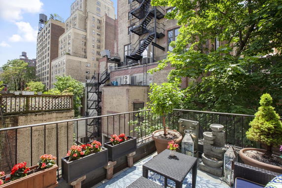 Rooftop patio with outdoor seating, plants, and views of adjacent buildings.