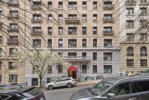 Front view of a multi-story residential building with a red awning entrance.