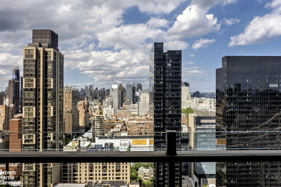 Panoramic view of city skyline with tall buildings under a cloudy sky.
