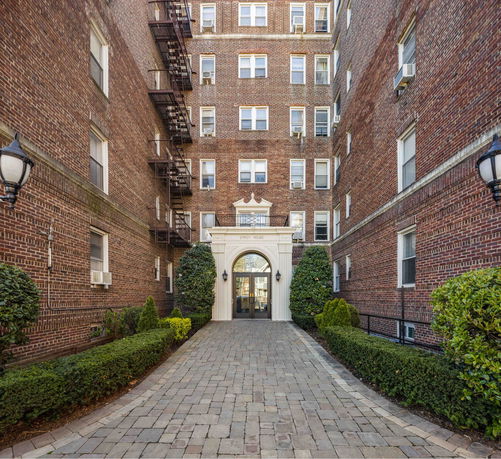 Front view of a multi-story brick apartment building with an arched entrance.