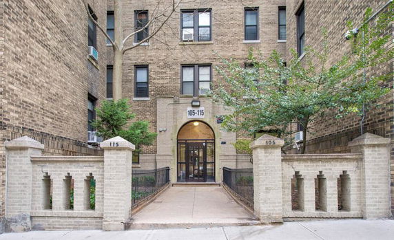 Front view of a multi-story brick building with an arched entrance.
