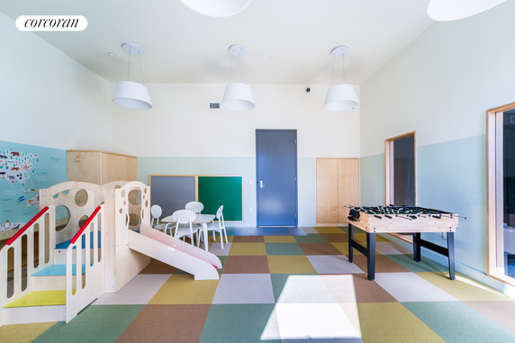 Indoor play area with a small slide, chairs, and a foosball table.