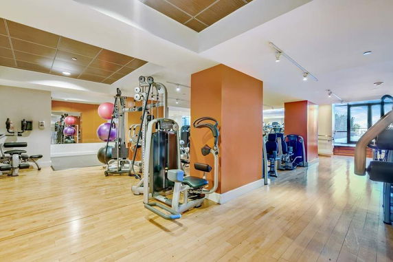 Indoor gym area with exercise equipment and wooden flooring.