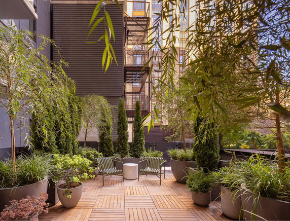 Outdoor sitting area with potted plants and surrounding building view