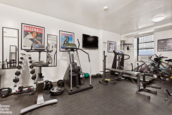 Room equipped with exercise machines and weights for a home gym setup.