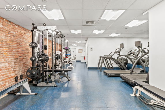 Interior view of a gym with exercise equipment and a brick wall.