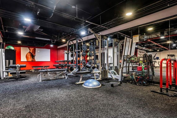 Indoor gym area with various exercise equipment and weights.