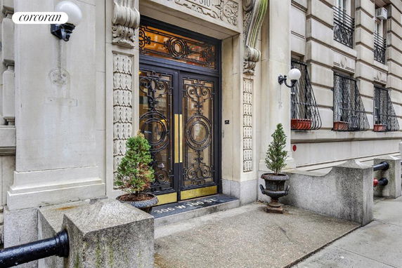Front view of a building entrance with ornate metal doors and decorative stonework.