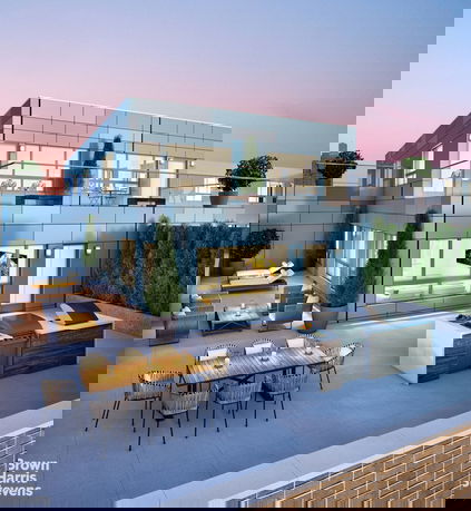 Rooftop view of a modern two-story building featuring outdoor seating and dining areas.