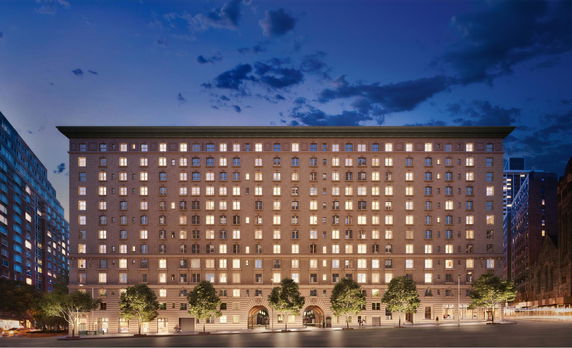 Front view of a multi-story building with numerous illuminated windows.