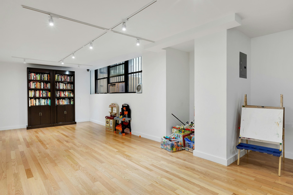 Room with wooden floor, bookshelf, and children's play area.