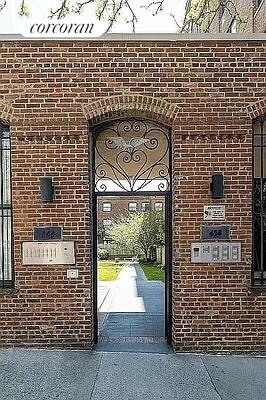 Front view of a brick building with an arched entrance and wrought iron gate.