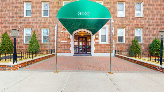 Front view of a brick building with a green awning over the entrance.