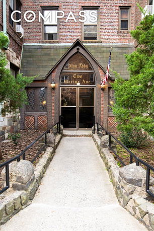 Front view of a brick building entrance with an American flag and pathway.