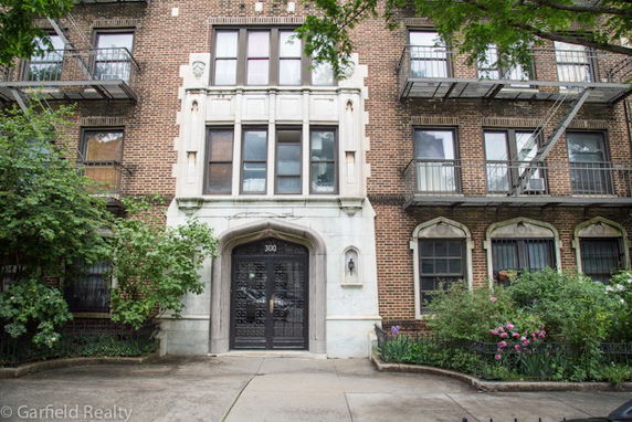 Front view of a multi-story brick building with decorative stone accents and wrought iron balconies.