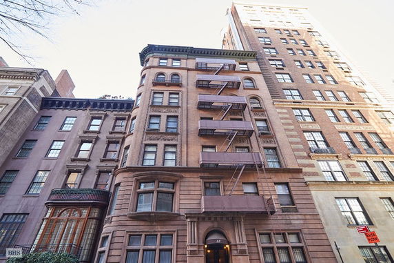 Front view of a multi-story brick apartment building with fire escapes.
