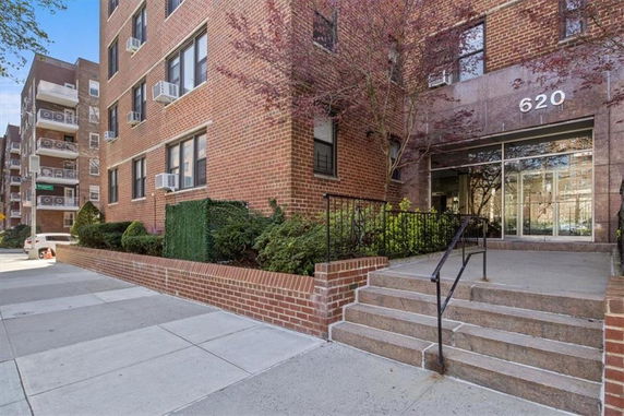 Front view of a brick apartment building entrance with stairs.