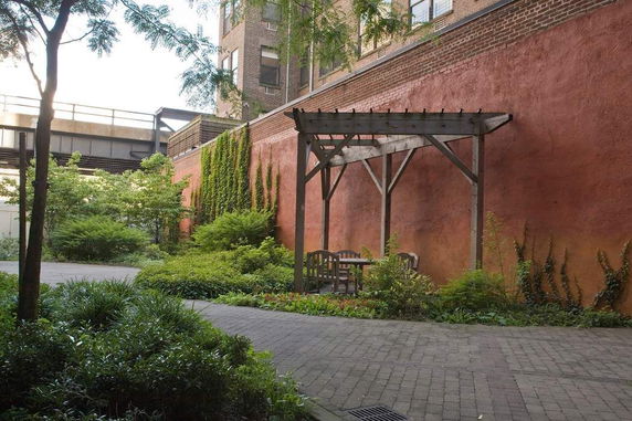 Outdoor area with a wooden pergola and seating next to a building.
