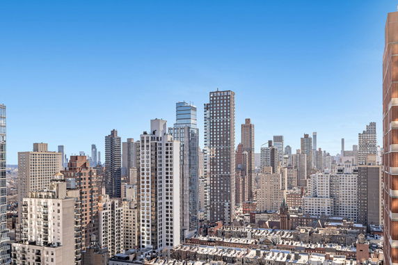 Panoramic view of a cityscape with numerous skyscrapers and buildings under a clear blue sky.