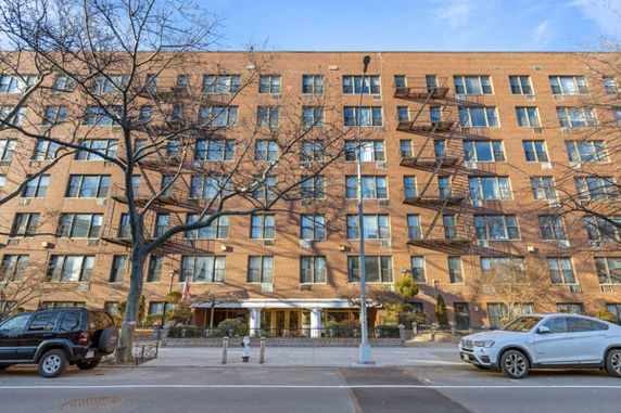 Front view of a multi-story brick building with several windows and fire escapes.