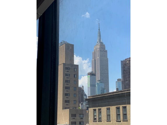 View of multiple buildings including a prominent tall skyscraper seen from a window.