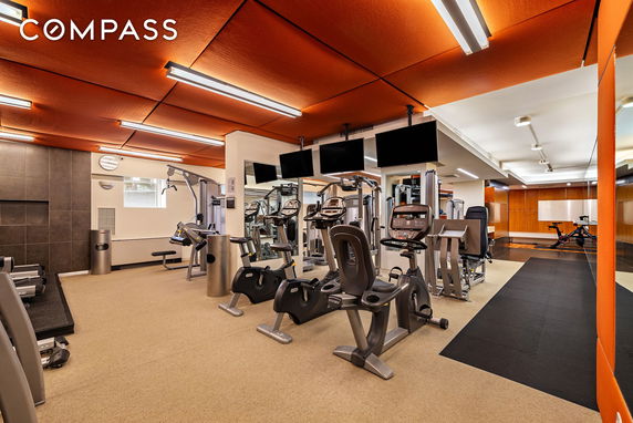 Interior view of a gym with exercise equipment and mirrored walls.