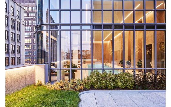 View of a modern building with large glass windows revealing an indoor swimming pool.
