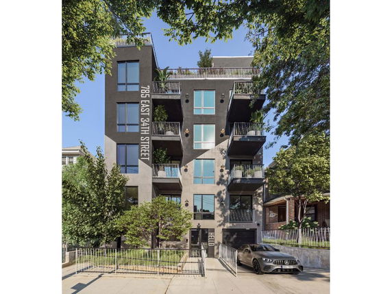 Front view of a multi-story building with balconies and a gated entrance.