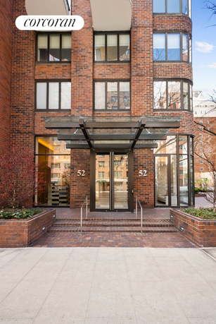 Front view of a multi-story brick building with a glass entrance canopy.