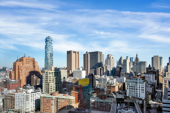 Panoramic view of a city skyline with multiple skyscrapers and buildings under a blue sky.